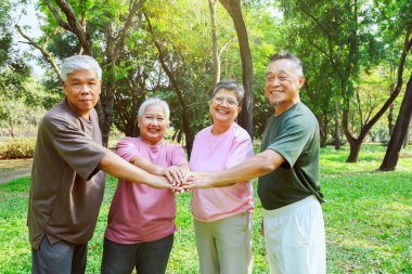 Neşeli Asyalı emekliler, sağlıklı olanlar el ele tutuşsun. Güçlerini birleştirip spor aktivitelerine katılın. Sabah sporun tadını çıkarın..