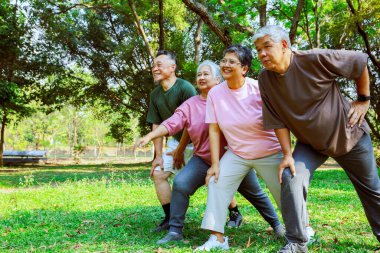 Dört yaşlı Asyalı yan görüş grubu gölgeli bir bahçede sabah egzersizi yapıyor bacak kaslarını esnetiyorlar ve dizlerini büküyorlar neşeli mutlu zihinlerle vücutlarını dengeliyorlar..