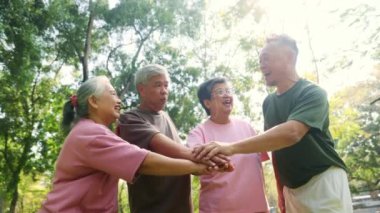 Neşeli Asyalı emekliler, sağlıklı olanlar el ele tutuşsun. Güçlerini birleştirip spor aktivitelerine katılın. Sabah sporun tadını çıkarın..
