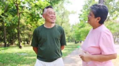 Bahçede sağlık, yürüyüş ve egzersiz: Bahçede birlikte egzersiz yaptıktan sonra ferahlatıcı su içen yaşlı çift: Sağlık emekliliği ve yaşlanma kavramı.