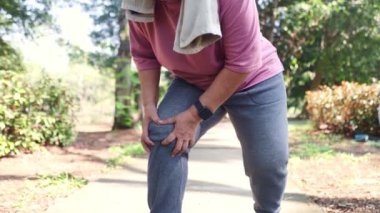 Yaşlı bir kadın parkta yürürken ve koşarken aniden diz ağrısı eklem ağrısı, eklem iltihabı, osteoartrit ve semptomları hafifçe masajla hafifletmek için koşmayı bırakmak zorunda kaldı..