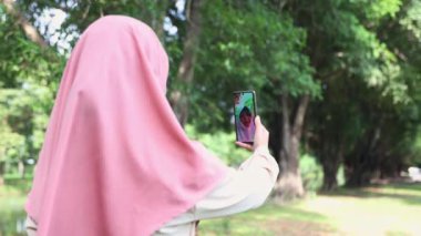 Müslüman kız ve anne, başvurudaki video çağrı sistemi aracılığıyla çevrimiçi konuşmak ve iletişim kurmak için akıllı telefon kullanıyor. Gülümseyen yüzler görürler, onları sevinçle selamlarlar..