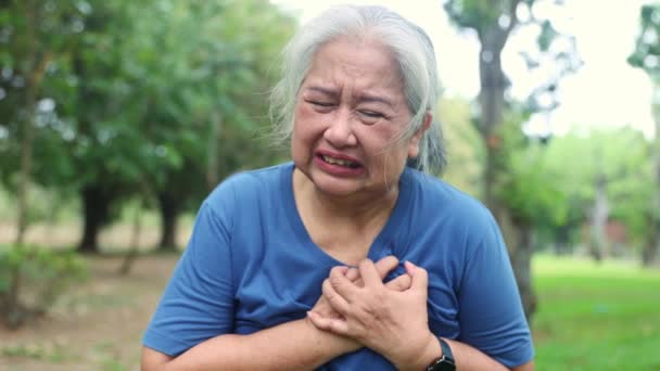 突然の心臓発作を起こした高齢女性の拷問された顔は 庭で運動した後 心筋の漏れの疲労と息切れの痛みを示しています 重度の症状は助けを求める — ストック動画