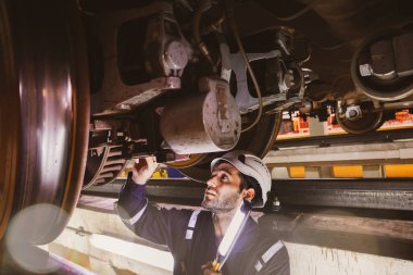 Erkek elektrikli araç bakım mühendisi, hafif ekipmanla motorun altında duruyor. Tamir garajındaki elektrikli araç fren kontrol sistemini kontrol edin..