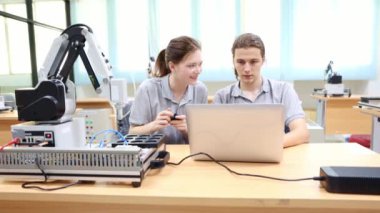 Tebrikler. İki erkek ve kadın öğrenci birlikte çalışıyor. Bilgi dizüstü bilgisayarına danışıyorlar..