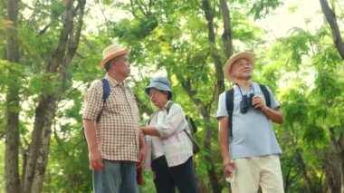 Grup kıdemli turistleri erkek ve kadın emekliler, akıllı telefondan gelen pusula ve GPS sinyalini kullanarak bir doğa çalışmasına danışmanlık yapmak için bir arada duruyorlar..