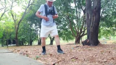 Gezgin, kıdemli Asyalı erkek turist zehirli bir karınca yuvasının üzerinde yürüyor alerjik bir reaksiyon gösteriyor ve dizleri ve bacakları kaşınıyor onu temizleyip uzaklaşmaya çalışıyor..