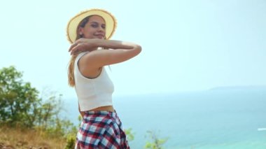 Adayı ziyaret eden dişi turist, yüksek açılı beyaz kumlu bir sahil manzarası ve güzel bir manzaradan hayrete düşen yüksek dağı görüyor. Ada kameraya keyifle bakıyor..