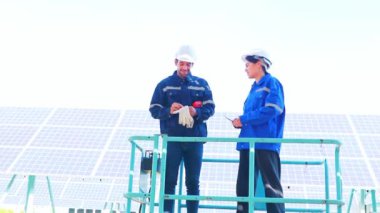Ekip erkek ve kadın elektrik mühendisleri sallantılı güneş panellerini kontrol ederken forklifti hazırlıyorlar. Güvenlik için yapıyı matkapla delmek için elektrikli matkap kullanıyorlar..