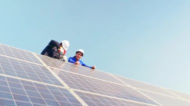 Ekip mühendisleri, sallantılı güneş panellerini kontrol ederken forkliftte çalışan erkek ve kadın elektrikçiler. Güvenlik için yapıyı matkapla delmek için elektrikli matkap kullanıyorlar..