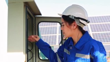 Elektrikli tornavida kullanarak güneş paneli kontrol panelini denetleyen kadın elektrikçi: Açık hava güneş paneli kurulum istasyonunda çalışan kadın mühendis portresi.