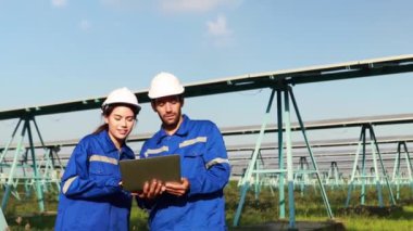 Endüstriyel mühendisler erkek ve kadın teknisyenler güneş pili bölgesini kontrol ettiler. Dizüstü bilgisayarları ayakta tutuyorlardı ve yapısal istikrarın korunması için planlama işleriyle ilgileniyorlardı..