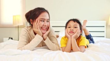 Mutlu aile anı, anne ve küçük kızı Asyalı elleri çenelerini tutarak yatağa uzanıp birbirlerini taklit ediyorlar..