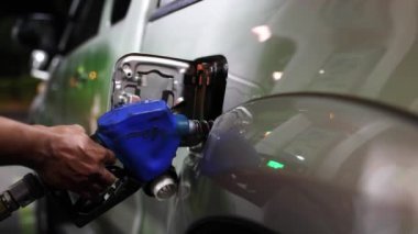 Kamyonet gece bir benzin istasyonunda durur: erkek işçinin eli benzin doldurma limanından bir kamyonetin dizel yakıt tankına yavaşça yakıt hortumunu çıkarır.