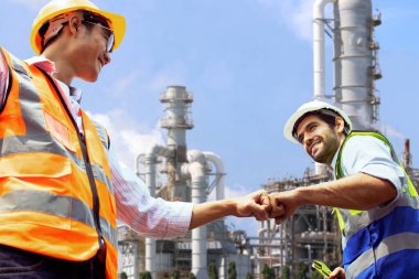 Takım çalışması Kafkas erkek mimar ve Asyalı mühendis yumruk tokuşturma iş arkadaşı başarı için endüstriyel emlak enerji rafinerisinde petrol rafinerisi projesinin planlanmasında pozitif tavır..