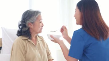 Hasta yaşlı kadın, kendisine bakan kadın hemşireyle yakından ilgileniyor. Yavaşça lapayı ağzına sürükler besleyici bir kahvaltı hazırlar. Evdeki hastalığından kurtulmasına yardım et..