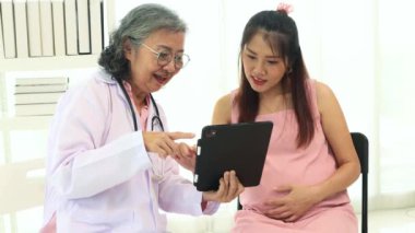 Başhekim jinekoloji hamile hastalarla görüşür. Hamilelik sağlığını, tabletleri kullanarak tartışır. Konforlu bir klinikte doğum öncesi tavsiyeler ve planlama sunar..