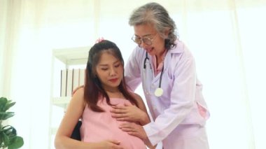 Kıdemli doktorun elleri stetoskop kullanarak fetüsün hareket halindeyken kalp atışlarını ölçer ve anne ve cenini değerlendirir: Mutlu anne doğum yapmadan önce doktoru ziyaret eder.