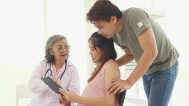 Kıdemli jinekolog hamile kadınlar ve kocalarıyla doğum öncesi kontroller için hastanede tanılar ve doğum öncesi sağlık ve hazırlıklar hakkında tavsiyelerde bulunur..