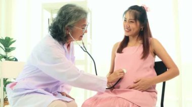 Başhekim hamile annenin kalp atışlarını ölçmek için steteskop kullanır ve anne ile fetüsün sağlığını ölçer: Mutlu anne doğumdan önce doktordan randevu alır.