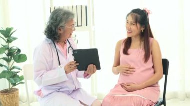 Başhekim jinekoloji hamile hastalarla görüşür. Hamilelik sağlığını, tabletleri kullanarak tartışır. Konforlu bir klinikte doğum öncesi tavsiyeler ve planlama sunar..