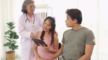 Kıdemli jinekolog hamile ve kocaları hastanede doğum öncesi bakımda stetoskop teşhisleri ile sağlıklarını kontrol ediyor ve doğum öncesi sağlık ve hazırlık konusunda tavsiyelerde bulunuyor..