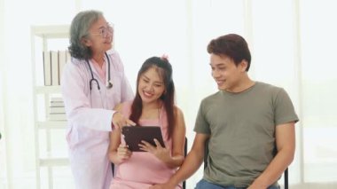 Kıdemli jinekolog hamile ve kocaları hastanede doğum öncesi bakımda stetoskop teşhisleri ile sağlıklarını kontrol ediyor ve doğum öncesi sağlık ve hazırlık konusunda tavsiyelerde bulunuyor..