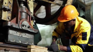 Erkek fabrika torna operatörü metal pul makinelerini çalıştırırken fındıkları sıkı tutmak için uzun kollu İngiliz anahtarı kullanır ve güvenlik için dikkatlice çalışır..