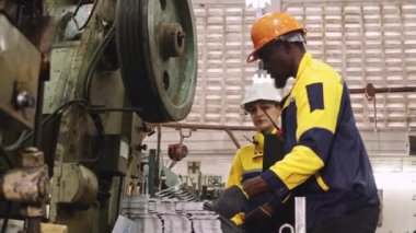 İki erkek ve kadın fabrika teknisyeni otomotiv parçaları imalat endüstrisindeki bir fabrikada metal damgalama makinelerini birlikte işletiyorlar..