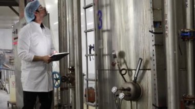 Erkek teknisyen, konserve balıkları üretim hattında sterilize etmek ve anormallikleri araştırmak için alet çantasıyla birlikte teçhizat buhar kazanını inceliyor. Konserve balık fabrikasının bakımını planlıyorlar..