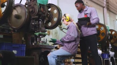 Erkek ve kadın büyük makine bakım teknisyenleri birlikte çalışmayı bırakın arızalı metal levha damgalama makinesini incelemeyi bırakın, verileri denetleme ve kaydetme görevlerini bölün çözüm bulun.