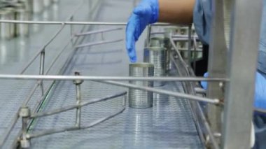 İşçi boş teneke kutuları seçiyor ve onları konserve balık fabrikasının yiyecek üretim sürecinde taze sardalya paketlemek için üretim hattına yerleştiriyor..