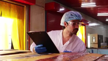 Ambalaj odasındaki erkek mağaza personeli, paketleme odasındaki konserve uskumru kutularını müşterilere teslim etmek üzere bir konteynır kamyonuna yüklemeden önce inceler ve kontrol ederler..