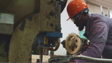 Erkek fabrika torna operatörü metal pul makinelerini çalıştırırken fındıkları sıkı tutmak için uzun kollu İngiliz anahtarı kullanır ve güvenlik için dikkatlice çalışır..