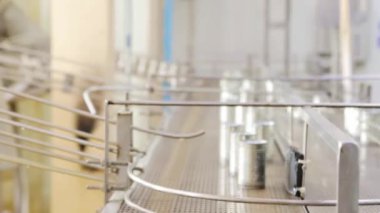 İçinde uskumru dolu alüminyum teneke kutular ve temiz kapaklar modern bir konserve fabrikasının temizliği için sıcak su temizleme noktasına bir taşıyıcı bant ile taşınır..