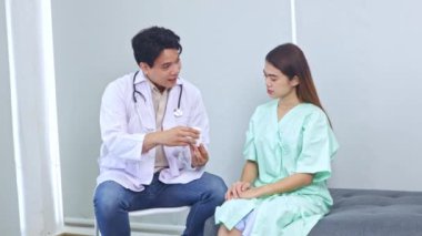 Erkek tıp uzmanı, hastanede iyileşmekte olan kadın hastalara tedavi ve ilaç tedavisi hakkında tavsiyelerde bulunuyor ve hastanın anlaması için örnek bir ilaç kutusu veriyor..