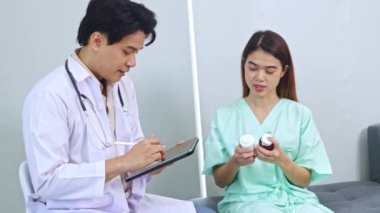 Erkek tıp uzmanı, hastanede iyileşmekte olan kadın hastalara tedavi ve ilaç tedavisi hakkında tavsiyelerde bulunuyor ve hastanın anlaması için örnek bir ilaç kutusu veriyor..