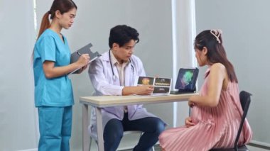 Erkek doğum uzmanı, jinekolog, fetal fetüs uzmanı hamile kadın ultrason sonuçlarını inceledi. Dizüstü bilgisayara ilgiyle baktı ve kadın hemşire asistanıyla görüşmeler yaptı..