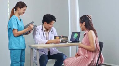 Erkek doğum uzmanı, jinekolog, fetal fetüs uzmanı hamile kadın ultrason sonuçlarını inceledi. Dizüstü bilgisayara ilgiyle baktı ve kadın hemşire asistanıyla görüşmeler yaptı..