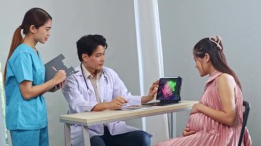 Erkek doğum uzmanı, jinekolog, fetal fetüs uzmanı hamile kadın ultrason sonuçlarını inceledi. Dizüstü bilgisayara ilgiyle baktı ve kadın hemşire asistanıyla görüşmeler yaptı..