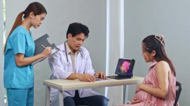 Erkek doğum uzmanı, jinekolog, fetal fetüs uzmanı hamile kadın ultrason sonuçlarını inceledi. Dizüstü bilgisayara ilgiyle baktı ve kadın hemşire asistanıyla görüşmeler yaptı..