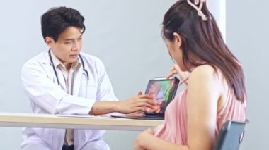 Erkek doğum uzmanı, jinekolog, anne fetüs uzmanı hamile kadını muayene ediyor, laptoptaki ultrason sonuçlarına faiziyle bakıyor ve doğum tarihini tartışıyor..