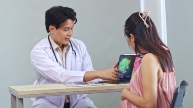 Erkek doğum uzmanı, jinekolog, anne fetüs uzmanı hamile kadını muayene ediyor, laptoptaki ultrason sonuçlarına faiziyle bakıyor ve doğum tarihini tartışıyor..