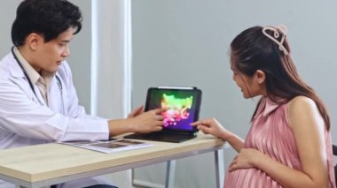 Erkek doğum uzmanı, jinekolog, anne fetüs uzmanı hamile kadını muayene ediyor, laptoptaki ultrason sonuçlarına faiziyle bakıyor ve doğum tarihini tartışıyor..