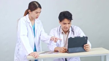 Kadın ve erkek doktorlar arasında bir hastane ofisinde toplanan doktorlar, tedavi edilen hastaları tartışıyor, dijital tabletler üzerinde tıbbi görevler üzerinde kararlılıkla birlikte çalışıyorlar..