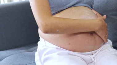 Hamile kadın karnına nazikçe nemlendirici sürüyor, karnında bebeğiyle nazikçe karnını okşuyor..