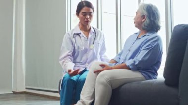 Kadın fizyoterapist klinikte kronik diz ağrısı olan yaşlı bir kadını tedavi ediyor. Bacaklarını esnetirken acı çekiyor, sıkıyor ve acı çekiyor. Huzursuz görünüyor..