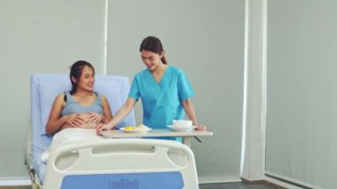 Bayan hemşire, hamile bir kadına doğum sırasında bakar. Yemek servisi sağlar ve yemek masasını hastanın yatağından uzaklaştırır. Boş vakitlerinde dinlenir ve dinlenir..