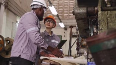 Erkek ve kadın endüstriyel parçalar fabrika teknisyenleri ekipman parçaları panolarını incelemek için birlikte çalışırlar..