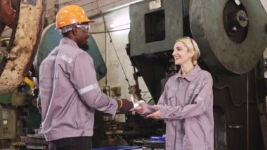 Erkek ve kadın işçiler, sanayi parçaları üretim tesisinde yıllık ikramiyelerini aldıktan sonra mutlu bir şekilde el sıkışıyorlar:.